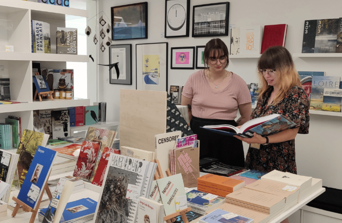 Librairie du CCCOD avec deux personnes consultant des livres d’art sur une table d’exposition